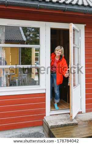 Woman looking out of a cabin door. Holidays in Scandinavian countries.