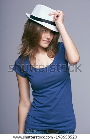 Beautiful young woman wearing summer fedora straw hat posing  in studio against gray background