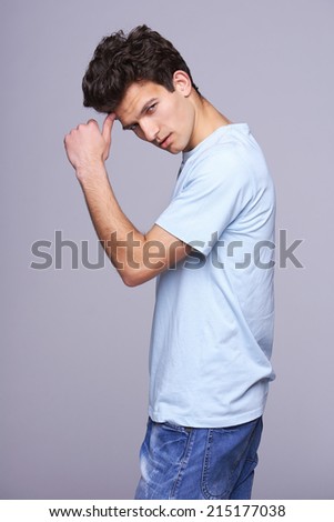Handsome man in blank blue t-shirt with modern haircut with hand on forehead looking skeptically distrustfulness
