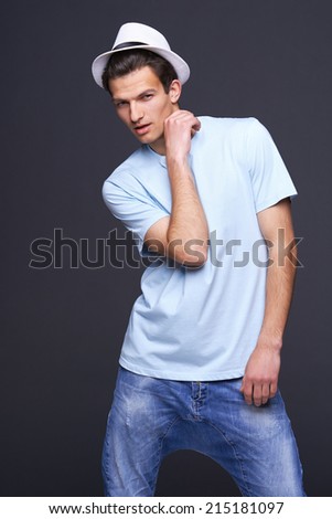 Man fashion model, stylish young man standing posing with hat, over black background