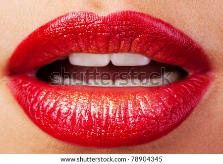 Closeup of lips with red lipstick and gold