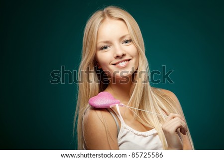 Fashion portrait of young blond female holding heart shape