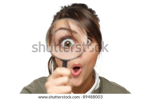 Funny image of young surprised female looking at the camera through a magnifying glass, isolated on white background