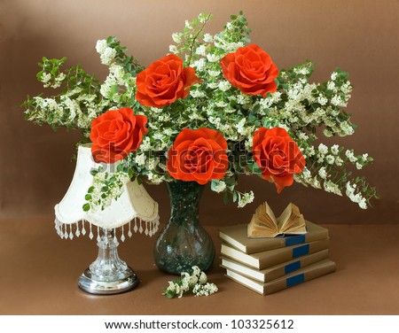 Still life with spring flowers and red roses bunch, antique lamp and book pile on painting background. Teacher day