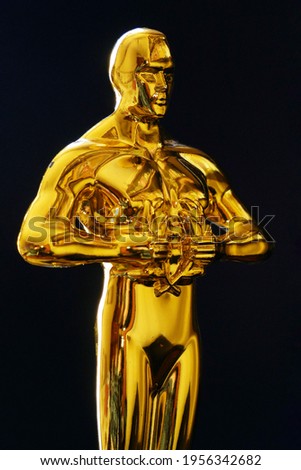 Hollywood Golden Oscar Academy award statue on black background. Vertical view. Success and victory concept.