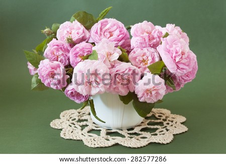Cream roses bunch in vase on green background. Still life with roses bouquet