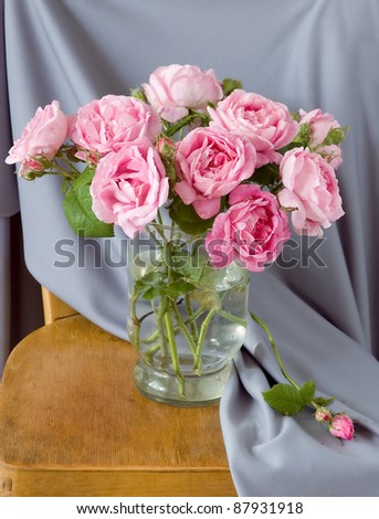 Bunch of tea roses in the vase on the chair draped in fabric
