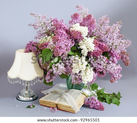 Still life with lilac flowers, book and antique lamp