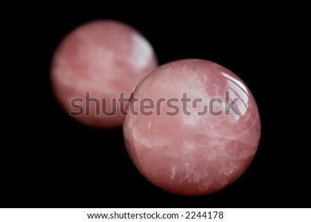Two pink zen stress balls, isolated over a black background. Originated from China, these balls are to be rolled around in the palm of one hand.