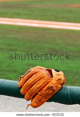 baseball glove on post in front of field