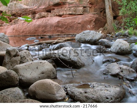 Water flowing over rocks in a red rock canyon.  Taken with a slow shutter so the water is motion blured.