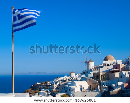 Nice view on blue and  white churches, hotels and houses of greek island, Santorini, Greece. Greek flag.
