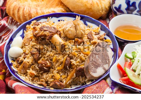 Uzbek national food pilaf and tea on the table with adras.