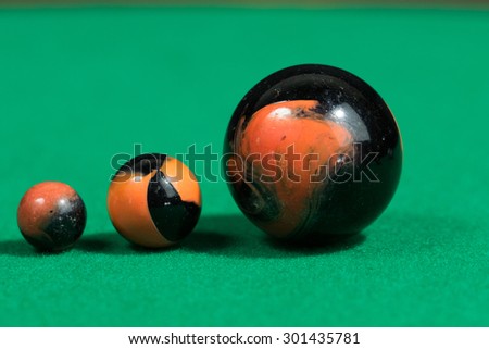 Bigger to smaller black and orange Marble Balls on green background