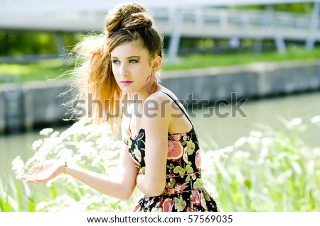 Teenager girl model presenting clothes in the park near the water and a bridge