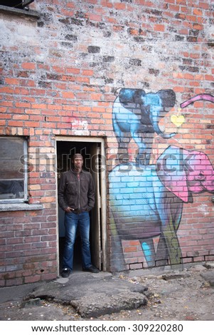 LANGA TOWNSHIP, SOUTH AFRICA - JULY 12, 2015 - A young man poses for a photograph in the doorway of a painted brick building in Langa, South Africa, a township located on the outskirts of Cape Town.