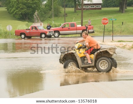 A four-wheeler turns around rather than trying to make it across a flooded roadway in rural Indiana.