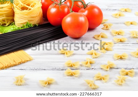 cuttlefish ink pasta and egg pasta with tomatoes on a white wooden background