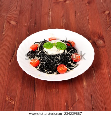 pasta made with cuttlefish ink with tomatoes and shrimp on the table with