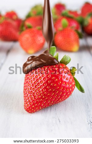 Strawberry in chocolate. Melted Chocolate pouring on fresh ripe juicy strawberry close up. Dessert. Gourmet food. Fondue