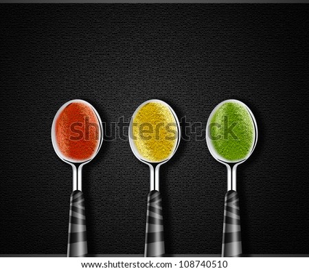 Collection of green, yellow and red spices on spoons on black background