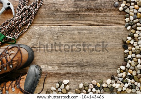 Rock climbing background with safety rope and traditional mountain hiking shoes on old wood board plank with alpine river pebbles