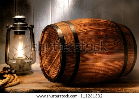 Old wood antique whisky wood barrel or rustic wine keg container with vintage kerosene lamp light lantern in smoke like fog in a smoky nostalgic American waterfront port wooden warehouse