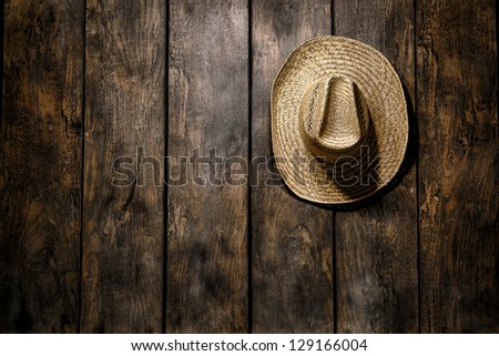 American West rodeo country farmer traditional straw hat hanging on distressed wood boards wall in a vintage ranch barn