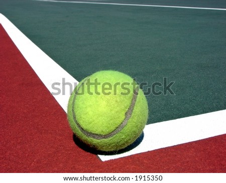 Yellow tennis ball on corner white line of red and green hard surface court