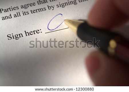 Fingers holding a pen and signing a document at the sign here line