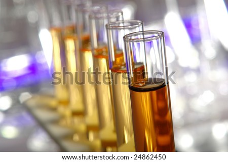 Laboratory glass test tubes filled with red and gold liquid on a rack ...