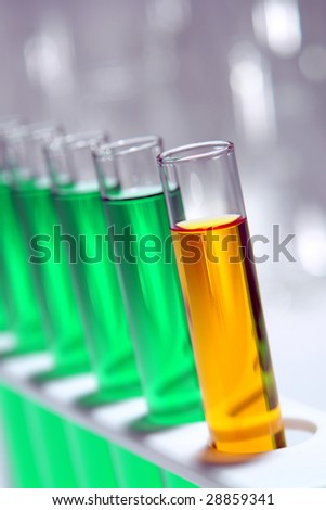 Laboratory glass test tubes filled with orange liquid and green chemical solution on a rack for an experiment in a science research lab