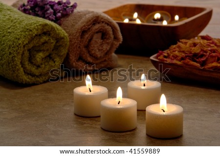 Aromatherapy scented candles burning with a soft glowing flame with towels and dried flowers for a relaxing ambiance and pampering wellness atmosphere in a spa