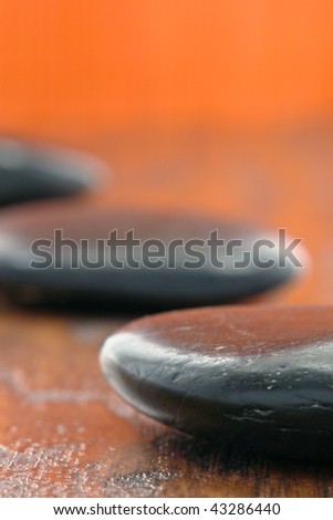 Black polished hot massage stones on wood surface in a spa