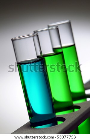 Laboratory glass test tubes filled with blue liquid and green chemical on a rack for an experiment in a science research lab