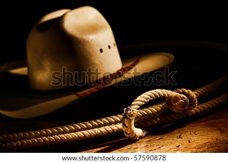 American West rodeo cowboy lasso rope and white straw hat in dramatic light with dark shadows