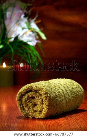 Soft green cotton towel on wood surface with candles burning for a pampering relaxation treatment in a spa