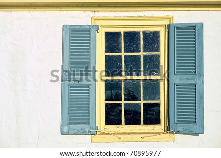 Old antique window with leaded glass panes and vintage wood shutters on a historic home colonial building