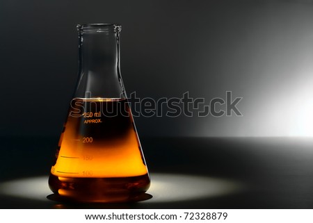 Scientific laboratory glass conical Erlenmeyer flask filled with amber orange chemical liquid for a chemistry experiment in a science research lab