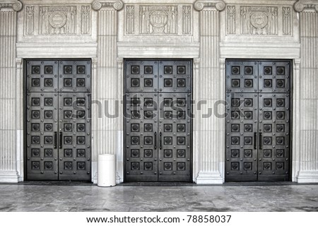 Massive monumental steel entrance doors on neo classical architecture style building with fluted ionic columns and decorative bas-relief frieze at the War Memorial building in Trenton in New Jersey