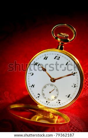 Antique open face gold pocket watch with Arabic numerals and open crystal on red damask fabric