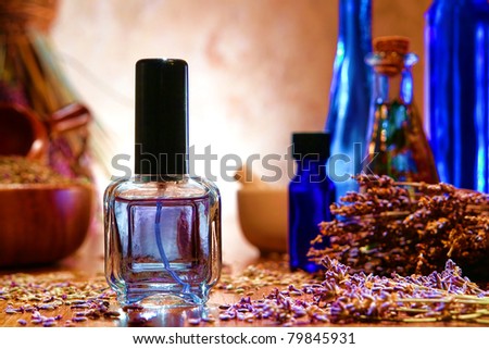 Perfume spray bottle filled with scented water and fresh lavender flowers with scattered seeds and blue bottles of natural essential oil in a traditional aromatherapy artisan shop