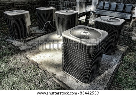 Battery of air conditioner condenser units outside an old building as part of a climate control cooling and refrigeration conditioning system