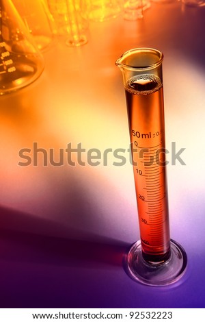 Scientific laboratory graduated cylinder filled with orange liquid for a scientific experiment in a science research lab