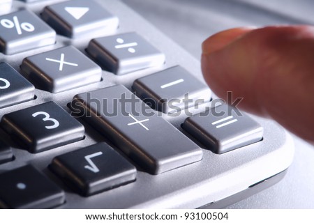 Man finger reaching over and ready to punch plus or equal signs keys on a calculator keypad