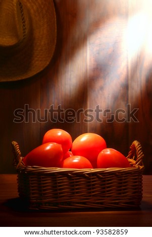 Organic plum tomatoes in an old wicker basket on a traditional country farm produce stand wood table in a vintage rural barn lit by soft diffused sunlight