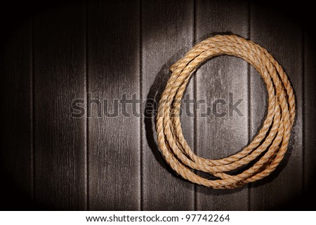American West rodeo natural hemp fiber rancher rope for ranching and steer roping on grunge vintage barn wood wall background
