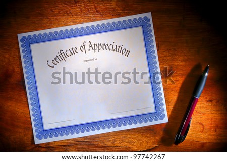 Certificate of appreciation reward blank paper document ready to fill out with text and ballpoint ink pen for signature on a wood desk