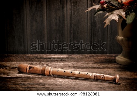 Old wooden recorder flute woodwind musical instrument with traditional classic baroque fingering holes on antique wood board table in vintage historic home in aged olde master still life paint style