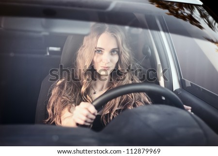 Woman driving car. Beautiful happy woman in car in the evening. Windshield view